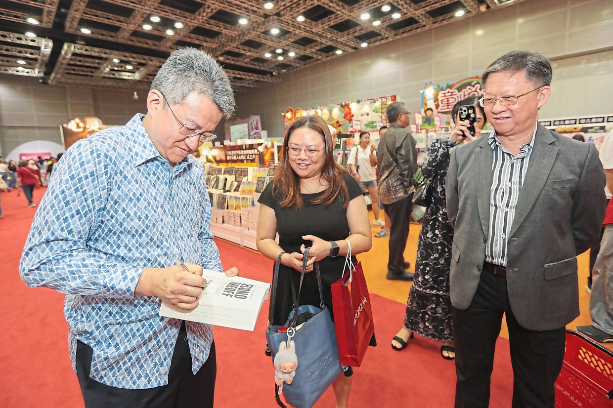 Personal touch: Deputy Investment, Trade and Industry Minister Liew Chin Tong signing a copy of his book ‘Second Takeoff: Strategies for Malaysia’s Economic Resurgence’ after it was nominated for an award at the 15th Popular-The Star Reader’s Choice Awards at Kuala Lumpur Convention Centre. Looking on are Star Media Group (SMG) group chief executive officer Chan Seng Fatt (right) and Chin.