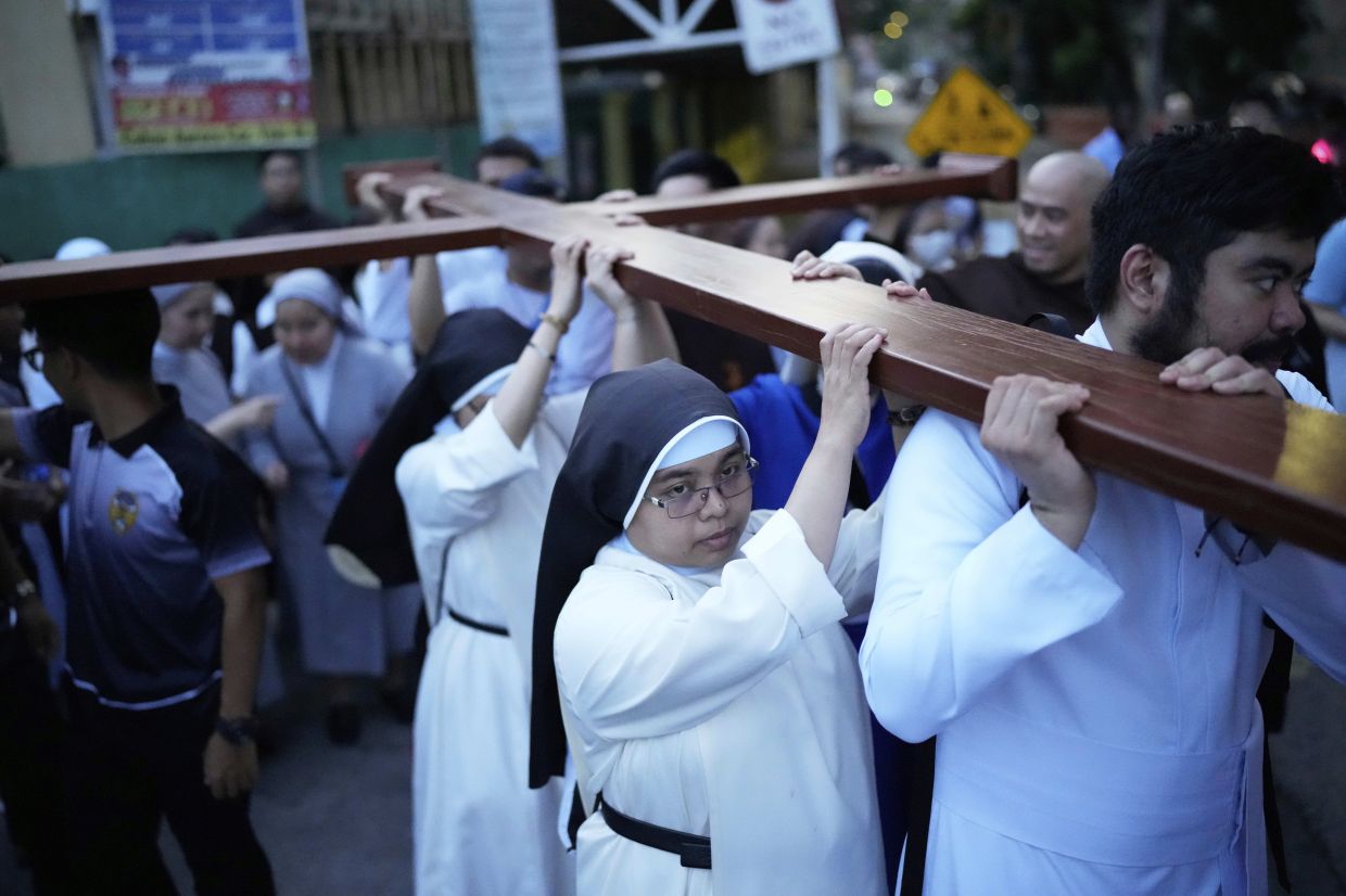 Catholic nuns help to carry a wooden cross during a religious procession as an act of penance and solidarity with the most vulnerable in society as part of their observance of lent in Quezon city, Philippines. -- AP Photo/Aaron Favila