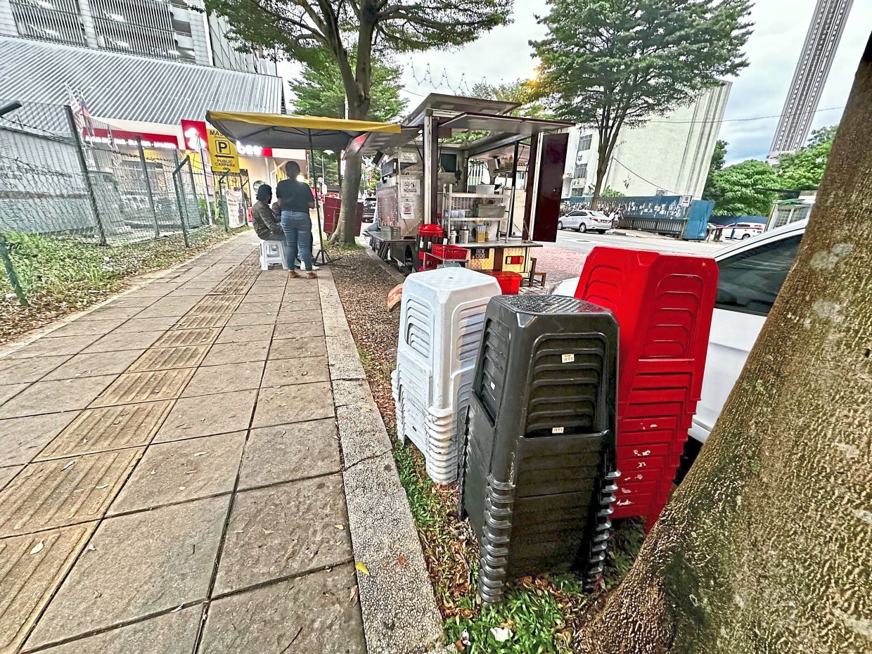 A food truck along Jalan Tun Sambanthan in Brickfields, with a canopy and seating with extra chairs stacked up nearby. The tactile paving is meant for pedestrian accessibility.