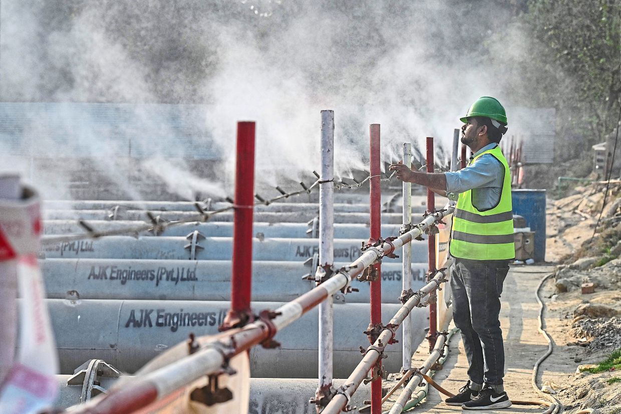 Dust buster: A worker adjusting an anti-smog dust suppression sprayer installed at a construction site in Lahore. — AFP