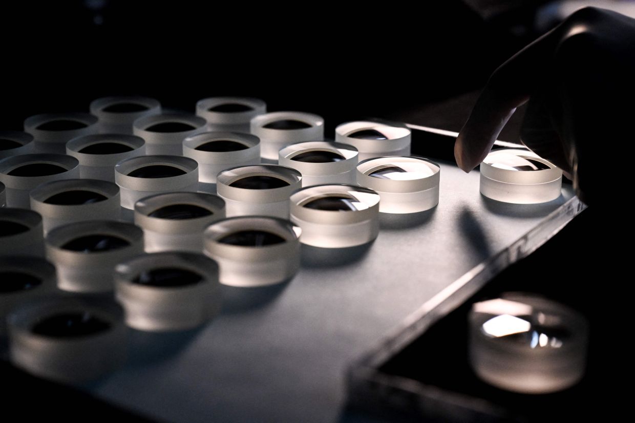An employee prepares a lens at the Leica factory in Wetzlar, western Germany.— AFP