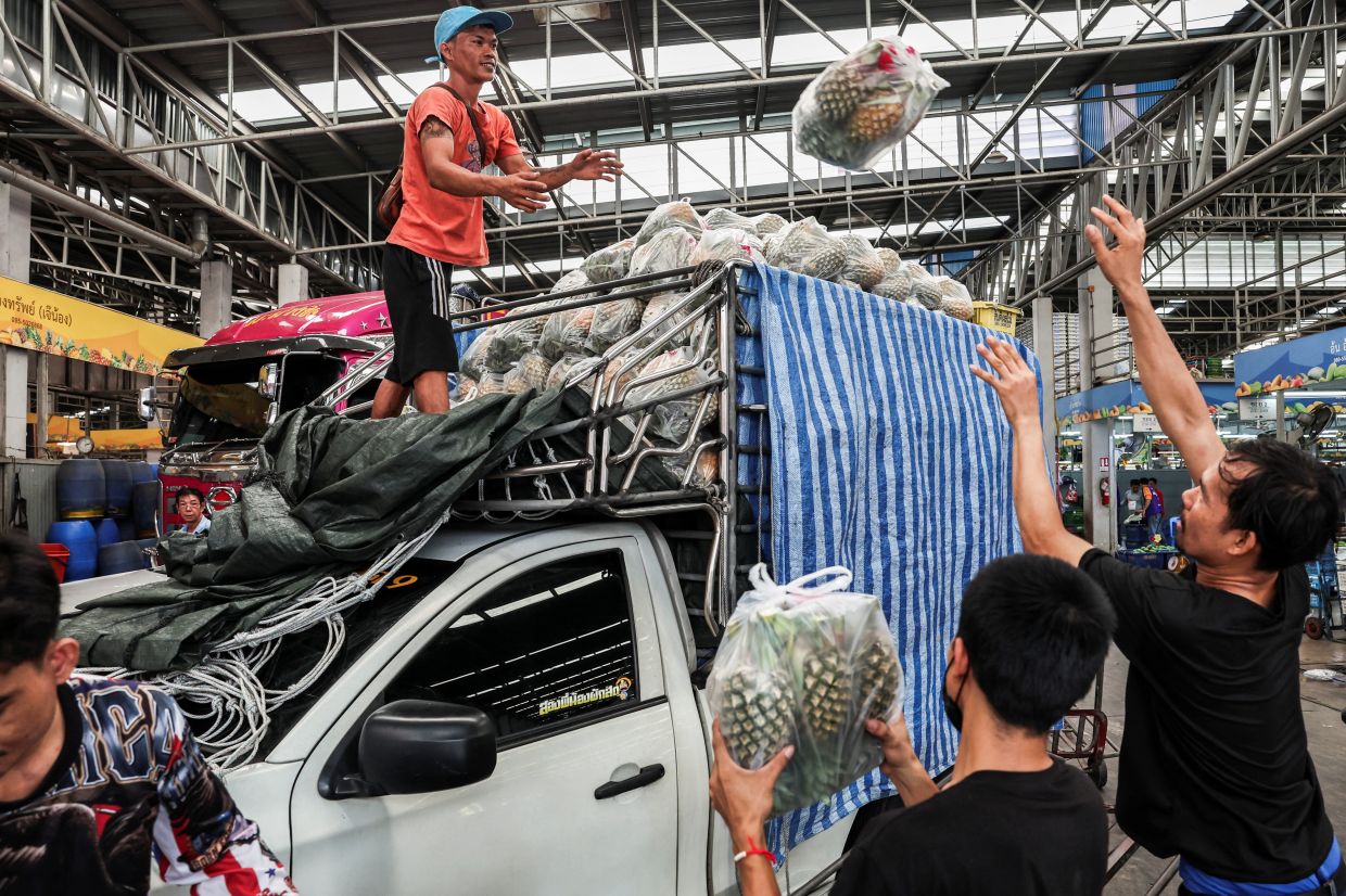 Shopkeepers load pineapples on a pickup truck at a wholesale market, following a tariff rate of thirty-seven percent imposed by US President Donald Trump, making Thailand one of the six countries in the South-East Asian region slapped with much higher-than-expected traffis by the US, in Pathumthani Province, Thailand, Monday, April 7, 2025. -- REUTERS/Chalinee Thirasupa