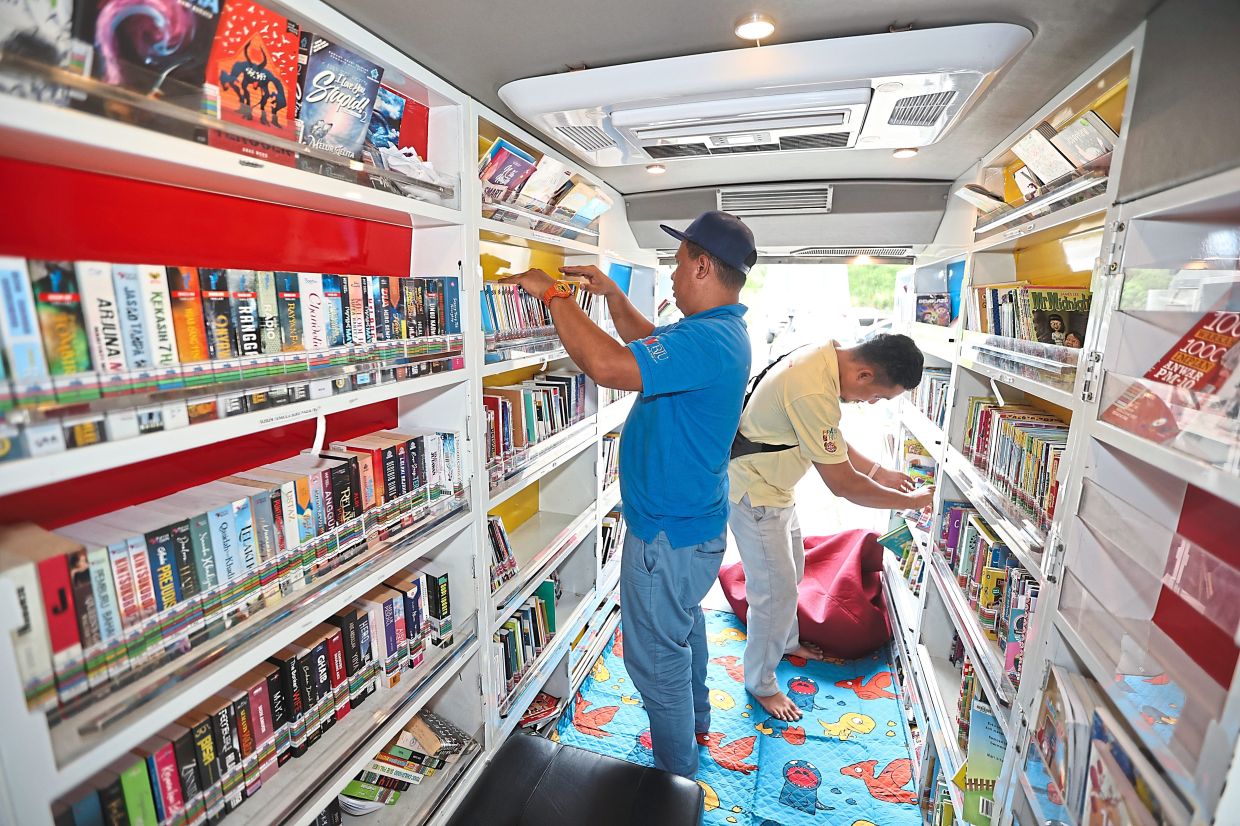 Firdaus (right) and Nik Azmani arranging contents of the mobile library.