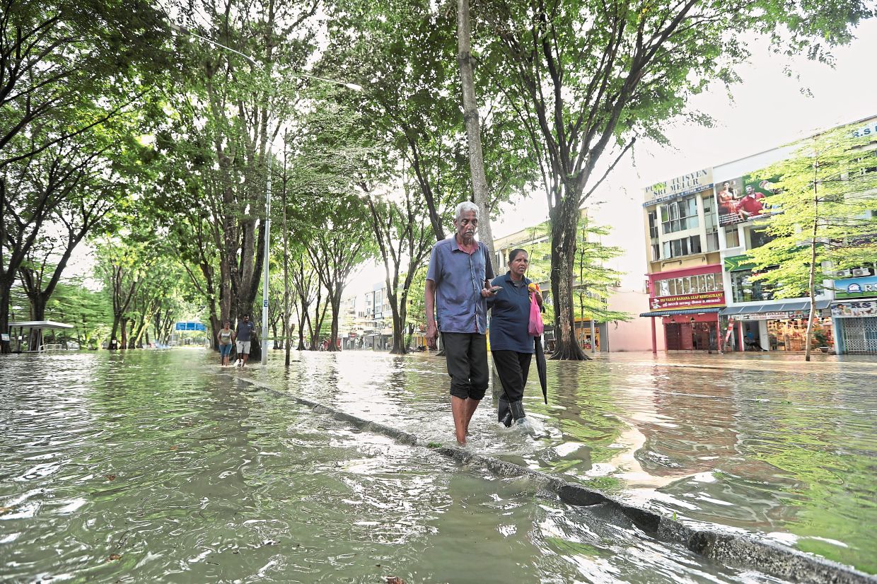 Boggy stroll: A couple wading through floodwaters in Taman Sri Muda, Shah Alam. — YAP CHEE HONG/The Star