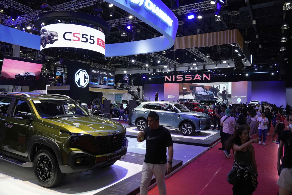 People check new vehicles during the Manila International Auto Show in Pasay city, Philippines. -- AP Photo/Aaron Favila