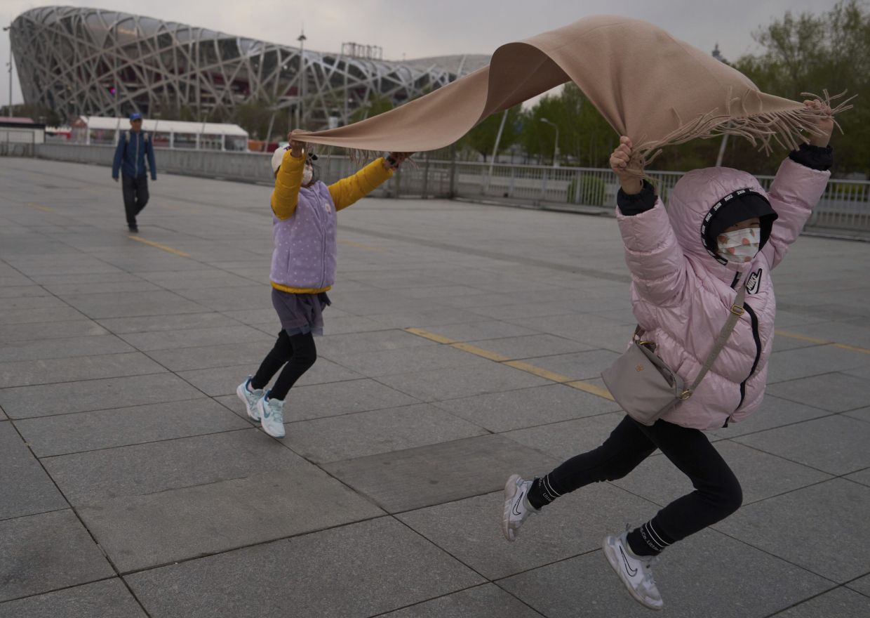 Children play with a scarf in strong winds near the iconic Bird's Nest National Stadium in Beijing, China, Saturday, April 12, 2025. -- AP Photo/Ng Han Guan