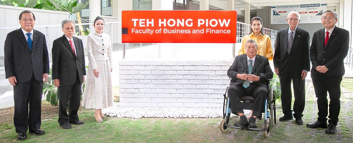 Remembering greatness: (From left) Chang, Tay, Diona, Ling, Ena, Sak and Prof Ewe posing for a photo by the new faculty signage.
