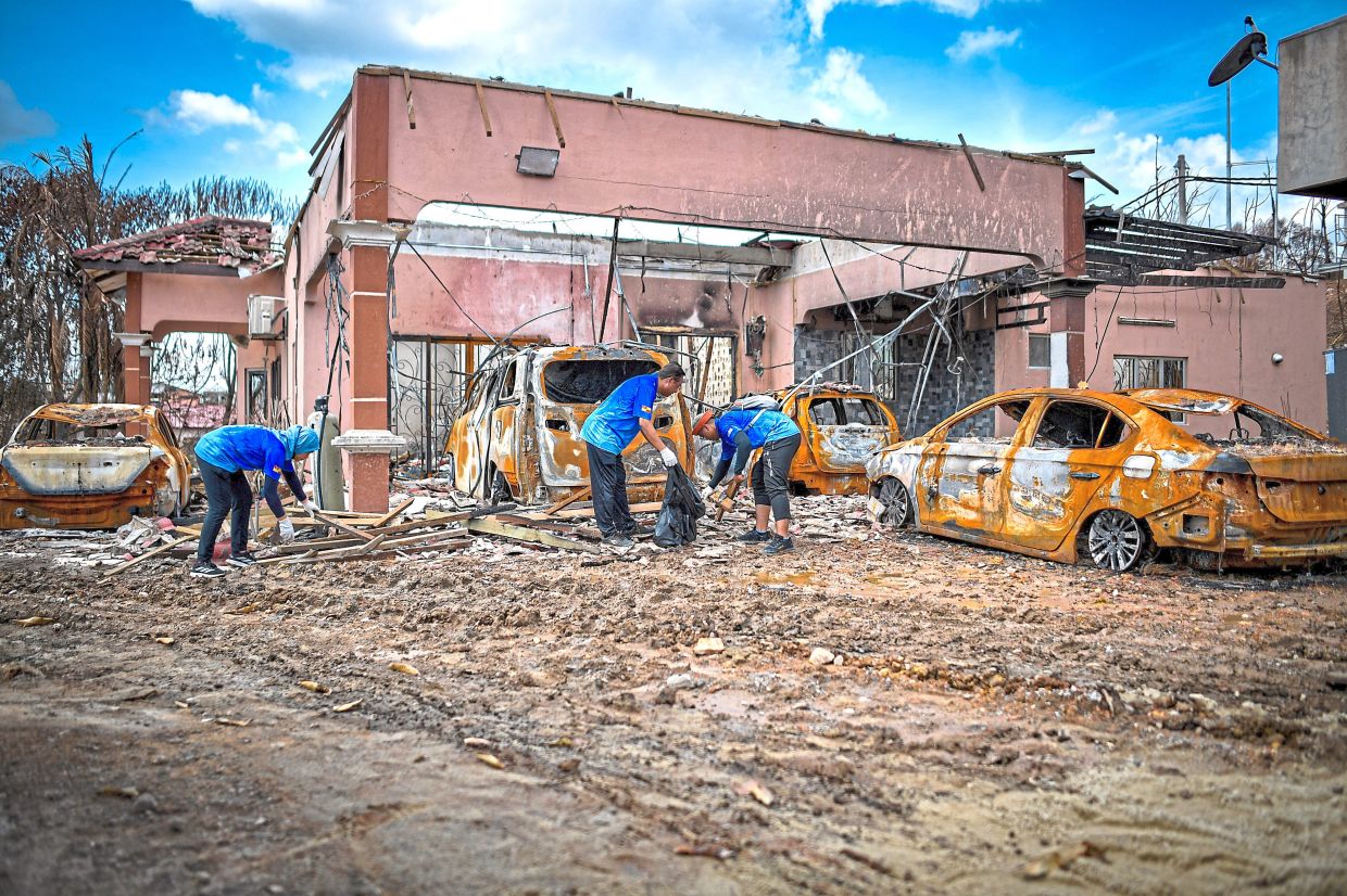 Team effort: Volunteers cleaning an affected area in Kampung Kuala Sungai Baru. — Bernama