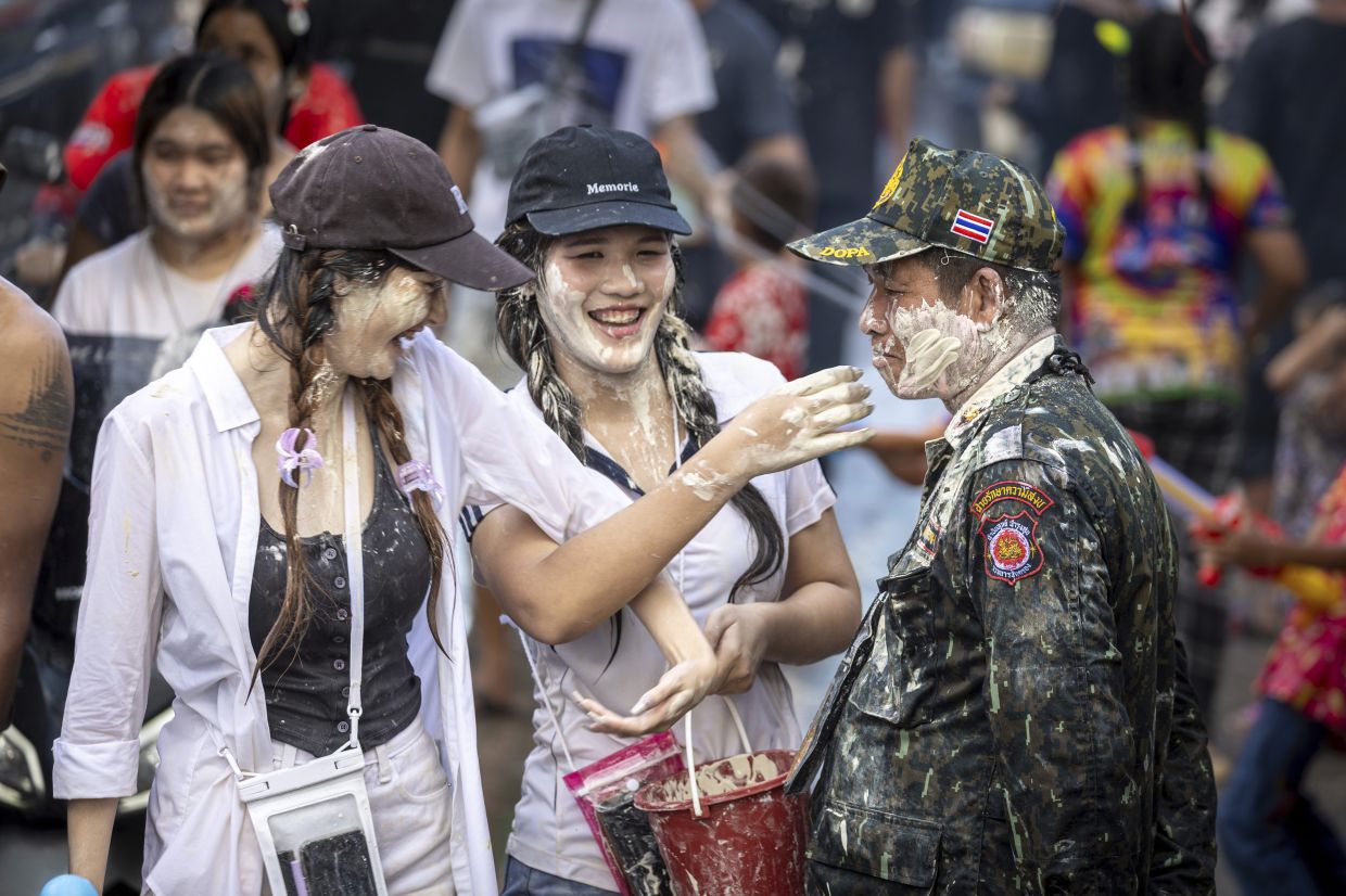 Thai woman put powder on the face of an officer during the Songkran water festival to celebrate the Thai New Year in Prachinburi Province, Thailand, Sunday, April 13, 2025. -- AP Photo/Wason Wanichakorn