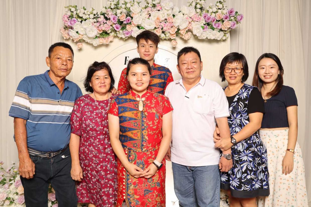 Khaw Fong Fong (third from left) and Cheah Jiang Wei (fourth from left) at their wedding reception. With them are the bride's parents Munil (left), his wife Pang Siew Lan (second from left) and family friends.