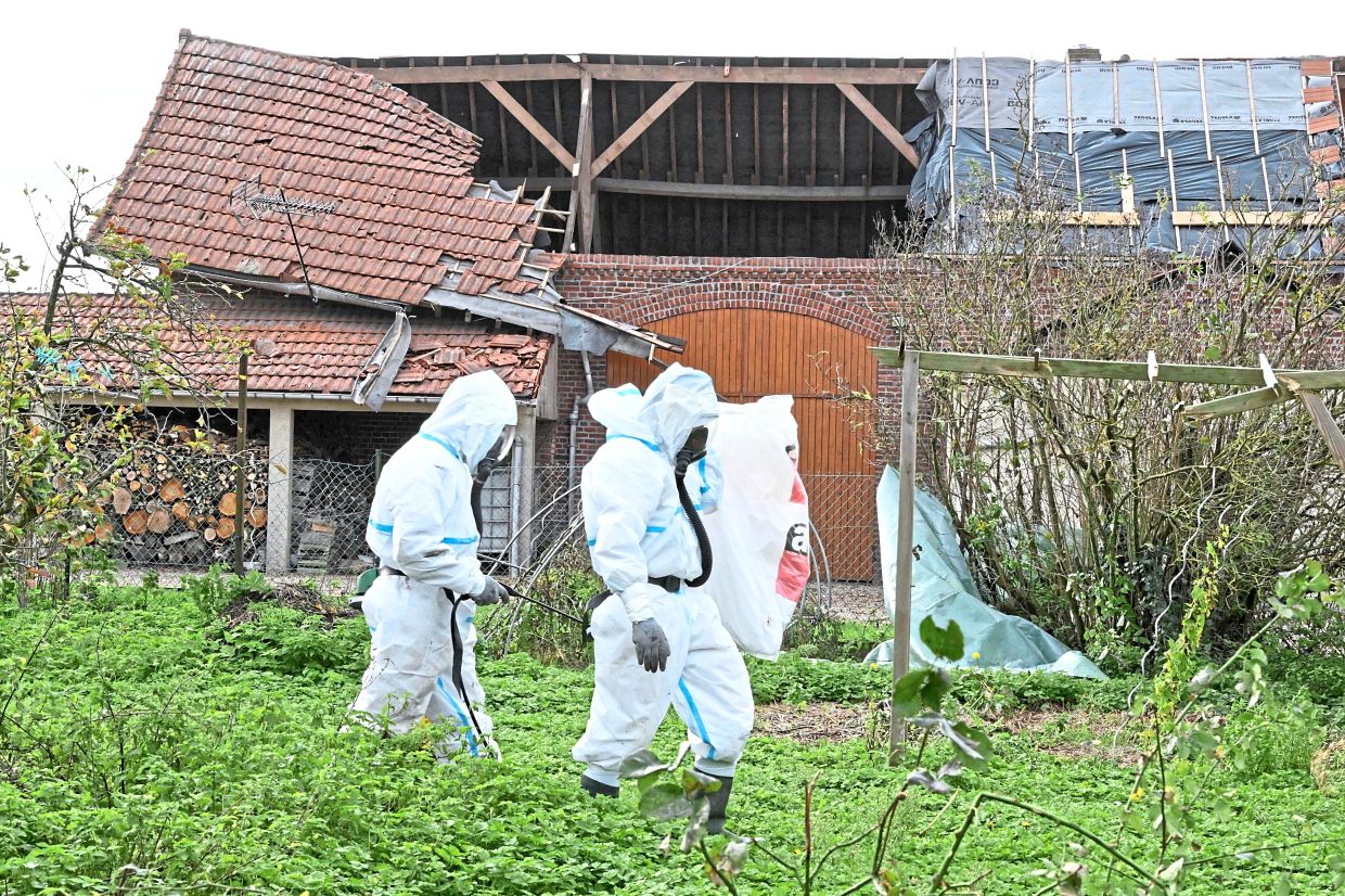 This is how dangerous France considers asbestos to be: Workers have to wear full protective gear to remove the material from an old building. — Filepic/AFP