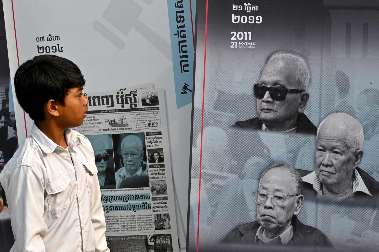 A student looking at a poster of former Khmer Rouge leaders during the outreach programme. - AFP