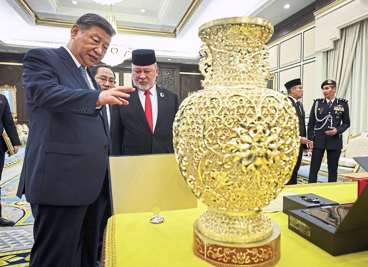 A gift: The King looking at the commemorative souvenir presented by Xi at Dewan Seri Maharaja, Istana Negara, Kuala Lumpur. — Bernama