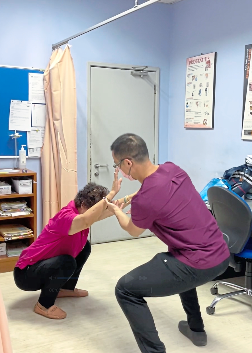 Dr Cheng teaches an octogenarian patient how to turn squatting into a structured exercise.