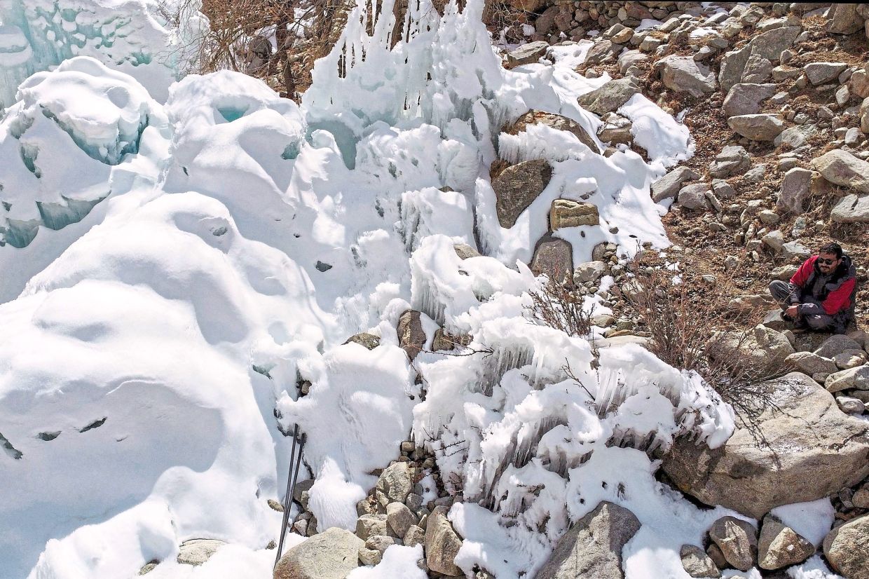Impressive feat: A man looking at an artificial glacier built by local residents during winter to conserve water for summer at Pari village in Kharmang district. — AFP