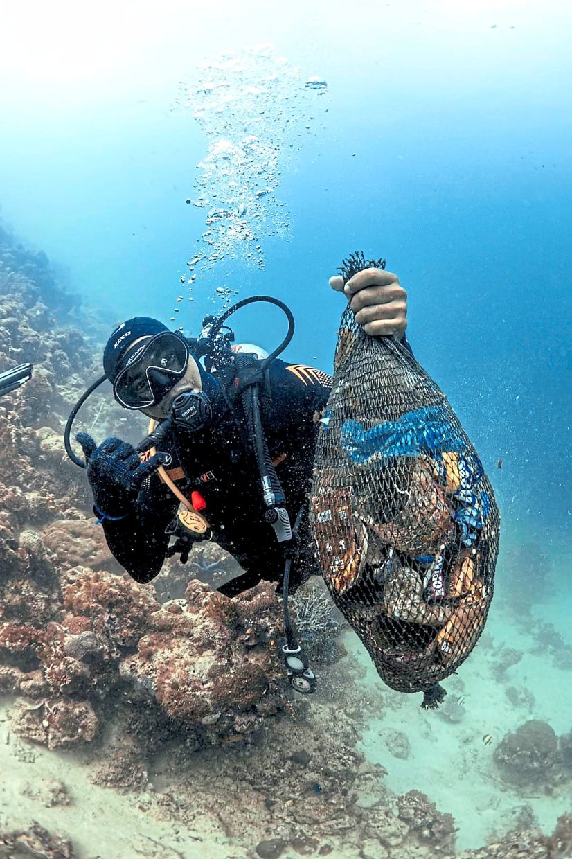 Taking out the trash: A diver holding up some of the rubbish found entangled between corals in waters off Mabul Island in Semporna.