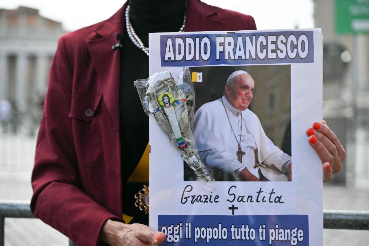 A woman holds a placard depicting a portrait of Pope Francis reading -- Goodbye Francis, thank you holiness, today all the people cry for you --at St Peter's square following the death of Pope Francis in the Vatican on Monday, April 21, 2025. Pope Francis died on April 21, 2025 aged 88, a day after making a much hoped-for appearance at Saint Peter's Square on Easter Sunday, the Vatican said in a statement. -- Photo by Andreas SOLARO / AFP