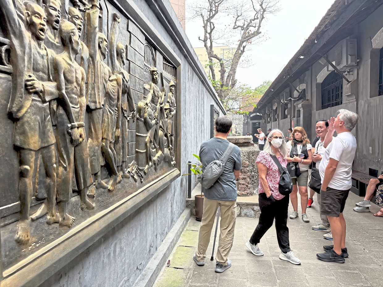 Tourists looking at an artwork at the Hoa Lo prison museum in Hanoi.