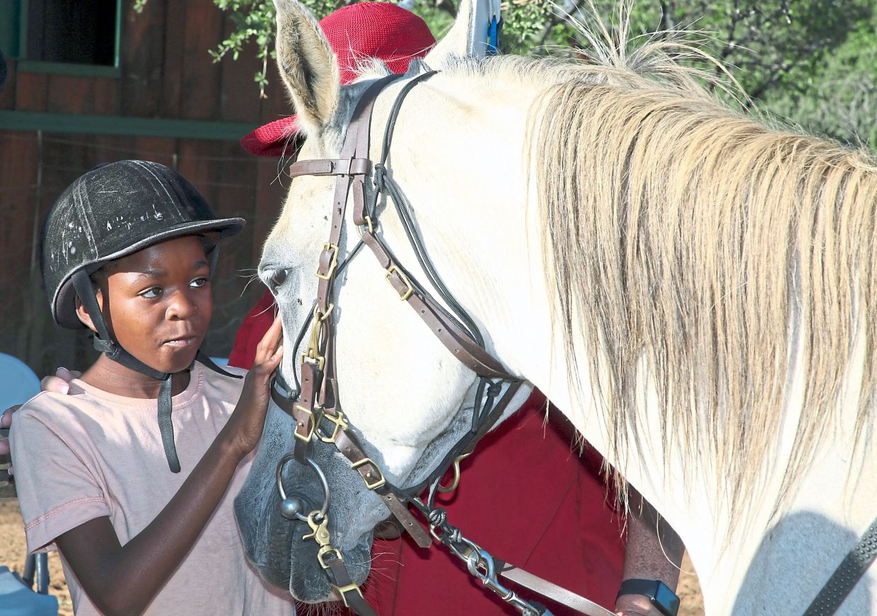 Merci who participates in the ‘Enabling Through the Horse’, therapy program, petting one of the animals horse.