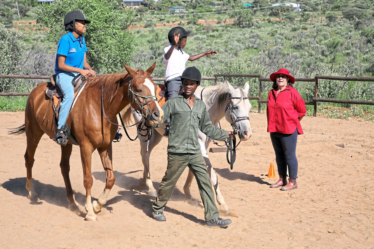 Program founder De Meyer (in red) grew up on a farm surrounded by horses.