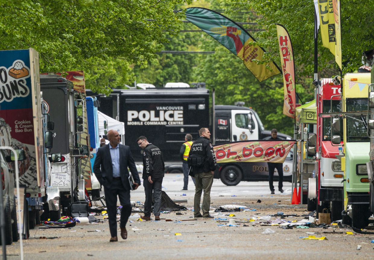 Vancouver Police detectives walking along where a car drove through a crowd killing multiple people on the weekend in Vancouver, on April 28, 2025. - AP