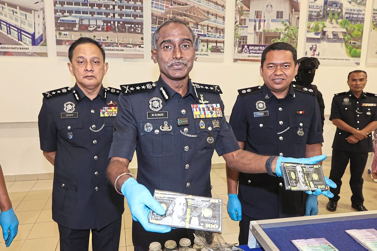Crime doesn’t pay: Comm Kumar (centre) showing US currency money packets used by a Singaporean suspect to traffic drugs, at the state police headquarters in Johor Baru. — THOMAS YONG/The Star