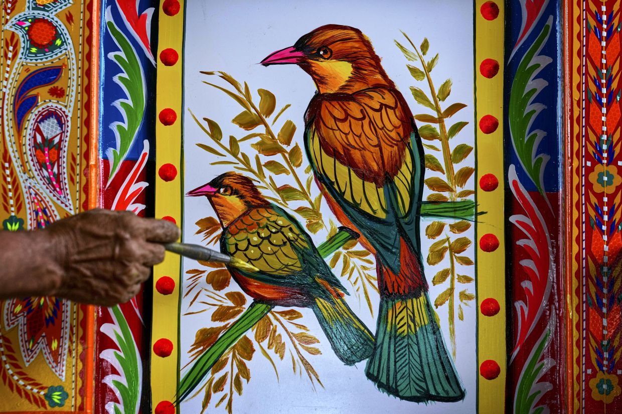 An artisan paints birds on a truck at a yard for workshops in Rawalpindi, Pakistan. Photo: AP 
