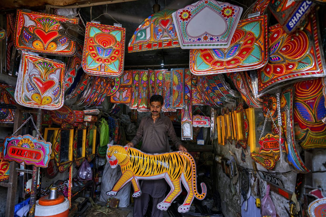 A vendor displays metal pieces painted in the style of traditional art used to decorate trucks at a shop in Rawalpindi, Pakistan. Photo: AP 