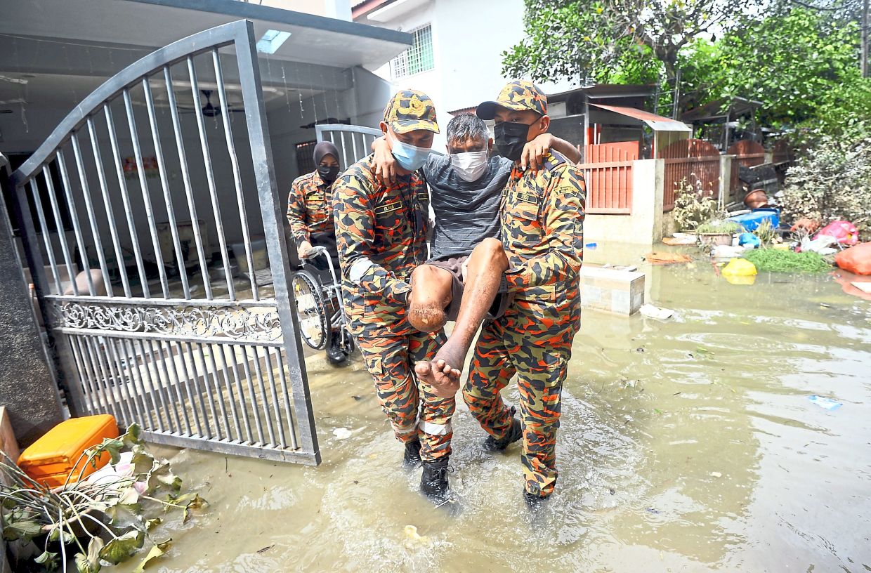 Firemen carrying an amputee to safety in Taman Sri Muda, Shah Alam, during the floods in 2021.