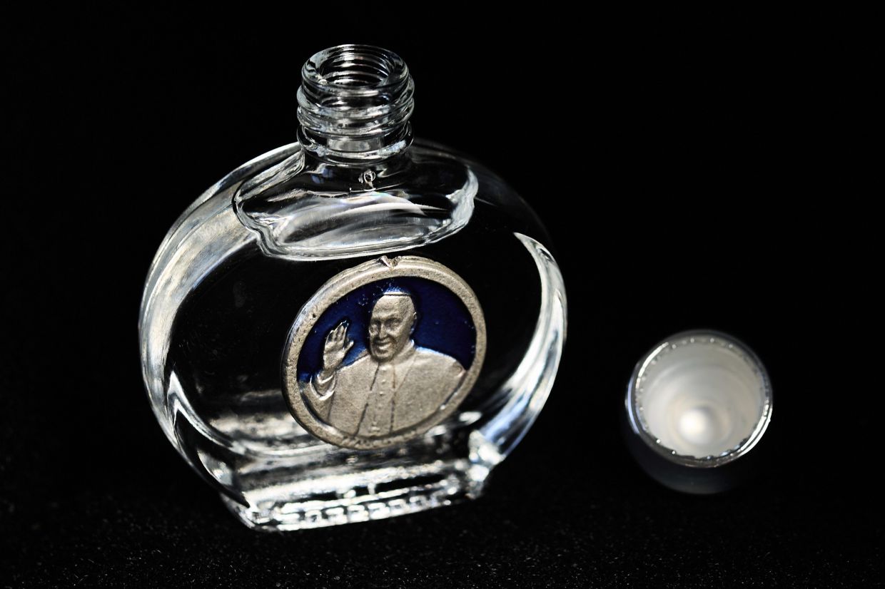 A religious souvenir, most likely a bottle of Holy Water, depicting Pope Francis on the front.