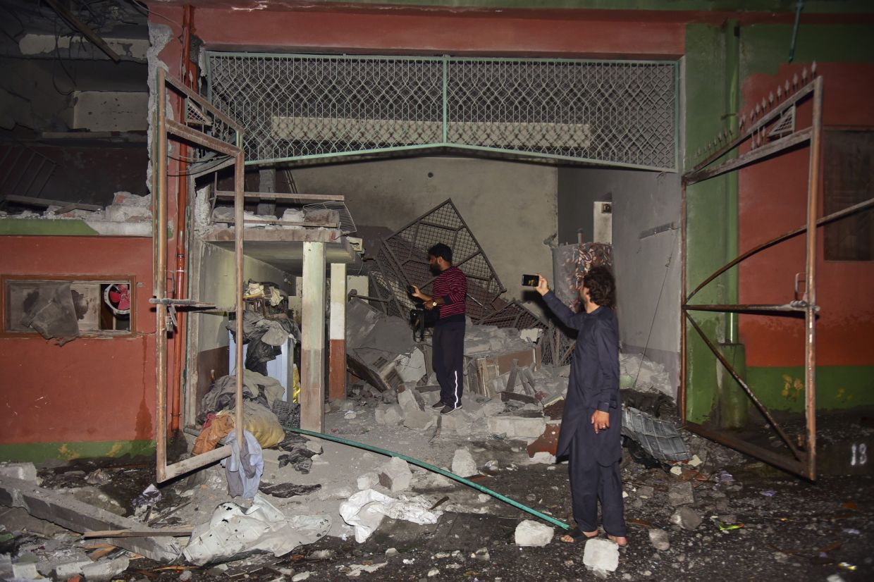 Members of media film a building damaged by a suspected Indian missile attack near Muzaffarabad. - AP