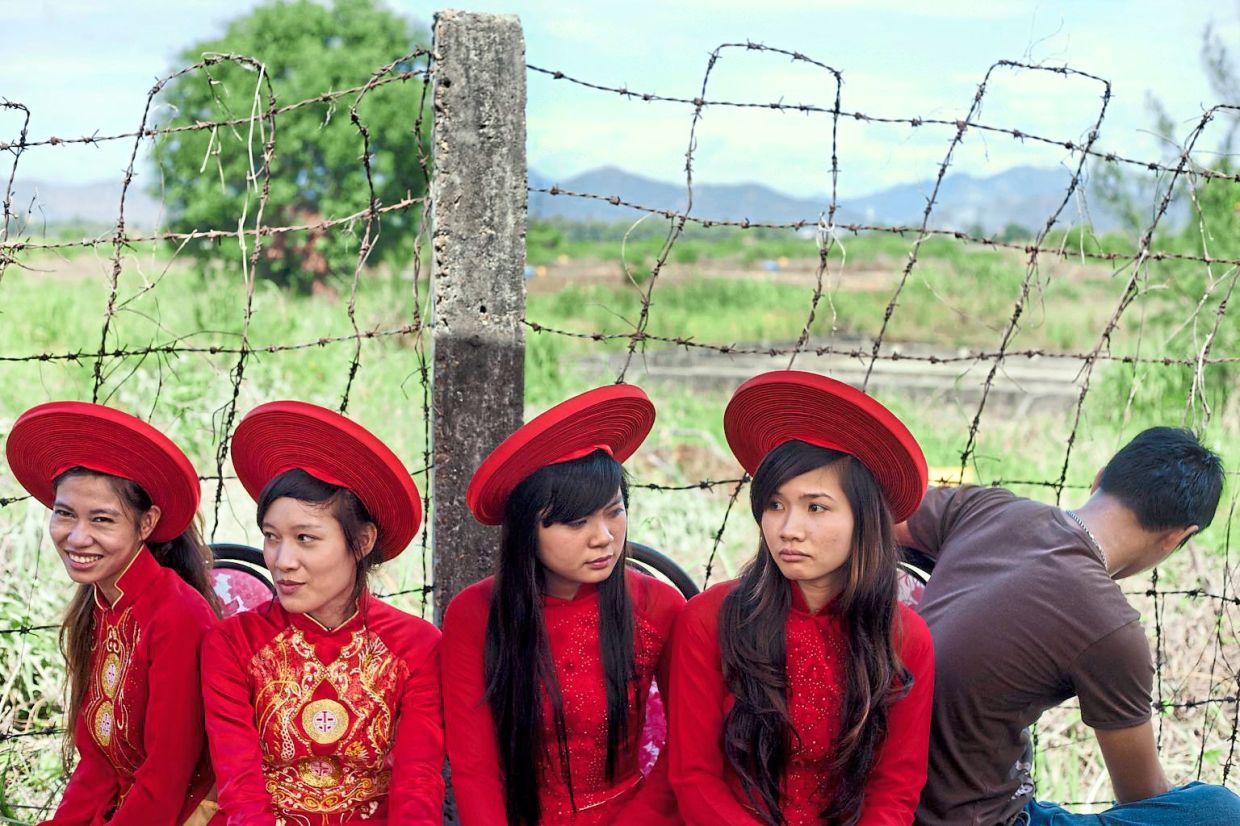 Long road ahead: Attendants sitting next to a field contaminated with dioxin before a ceremony marking the start of a project to clean up the toxin left over from the Vietnam War, at a former US military base in Da Nang, on Aug 9, 2012. — AP