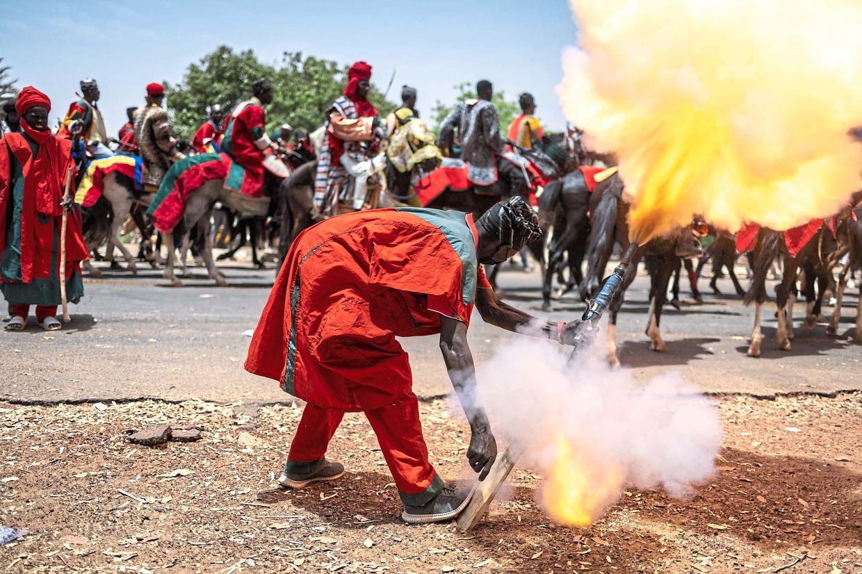 A royal hunter firing his hunting gun to announce the arrival of the Emir of Dutse during the Durbar horse procession. — AFP