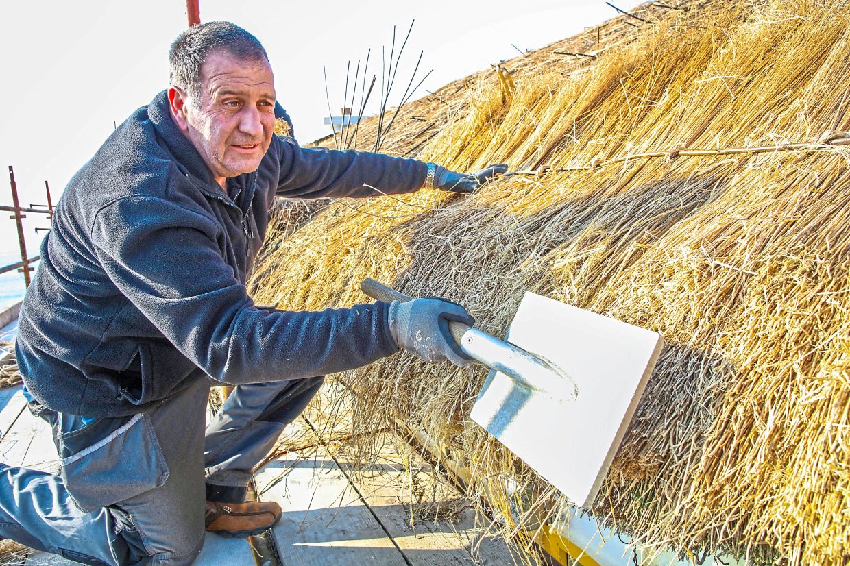 Kilpatrick working on the roof of a thatched cottage in Bunbeg. — AFP