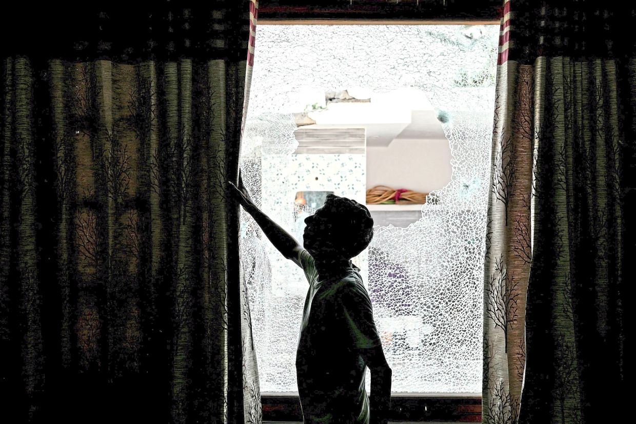 Aftermath: A man showing the shattered window of a house after cross-border shelling in Arnia town near the border area in India’s Jammu region. — AFP