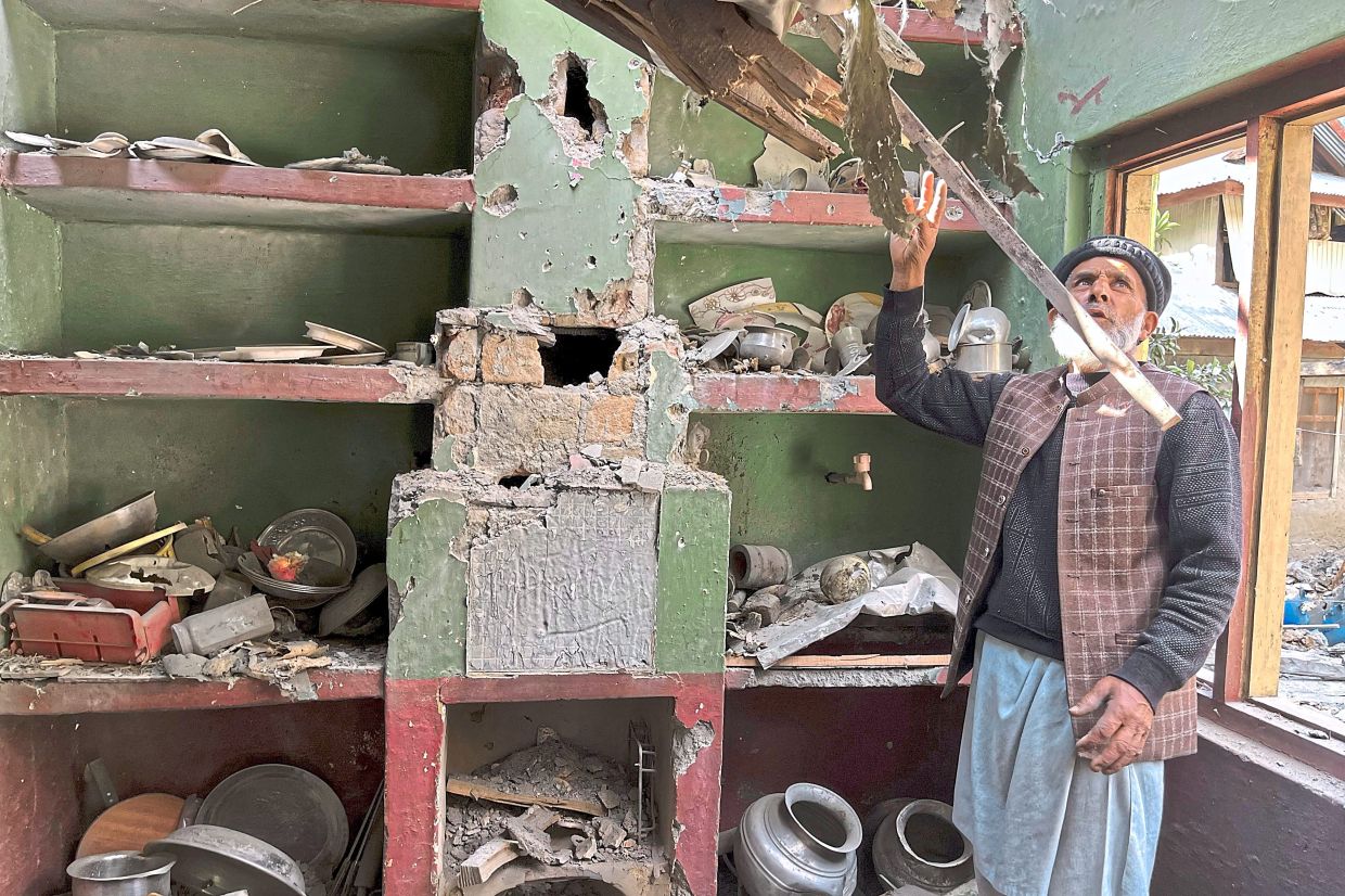 A Kashmiri villager examines the damage to his house caused by overnight Indian shelling in Shah Kot. -AP