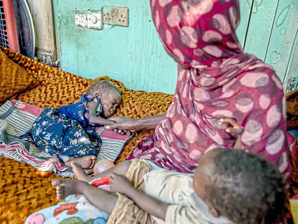 Khadija Mousa trying to comfort her severely malnourished daughter Fatima in the recently recaptured area of Jereif West in Khartoum, Sudan. — Ivor Prickett/The New York Times