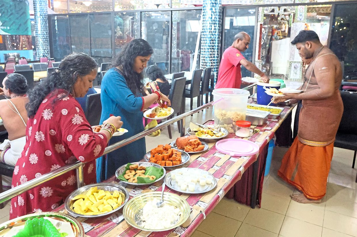 Devotees picking up some of the free food served at Arulmigu Sri Rajakaliamman temple. — THOMAS YONG/The Star