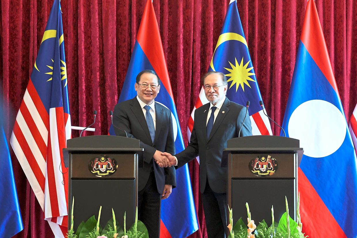 Forging stronger bonds: Anwar shaking hands with Siphandone after a four-eyed meeting.— Bernama