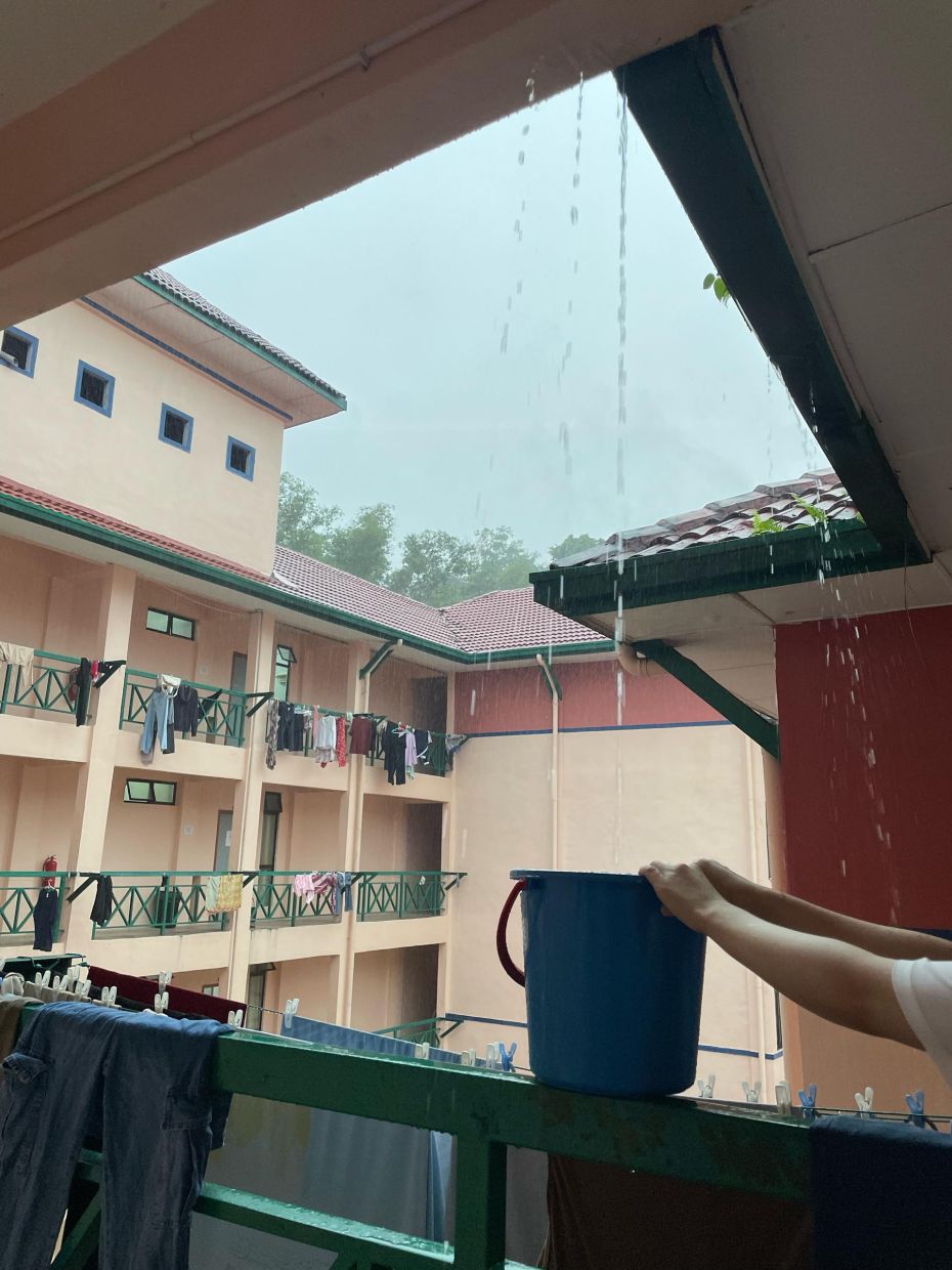 A student collects rainwater in a bucket from a dormitory balcony at UMS — a common practice due to inconsistent piped water supply on campus.