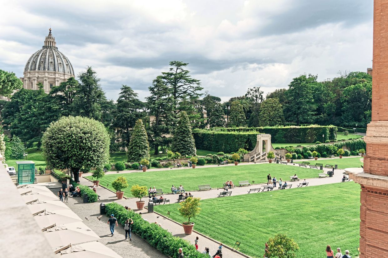Take a leisurely stroll at the Vatican Gardens with St Peter's Basilica in the background. — Unsplash