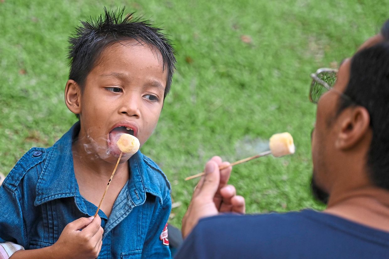 A child and his father enjoying the ‘Dragon’s Breath’, a dessert containing liquid nitrogen and served in a cup at the food festival.