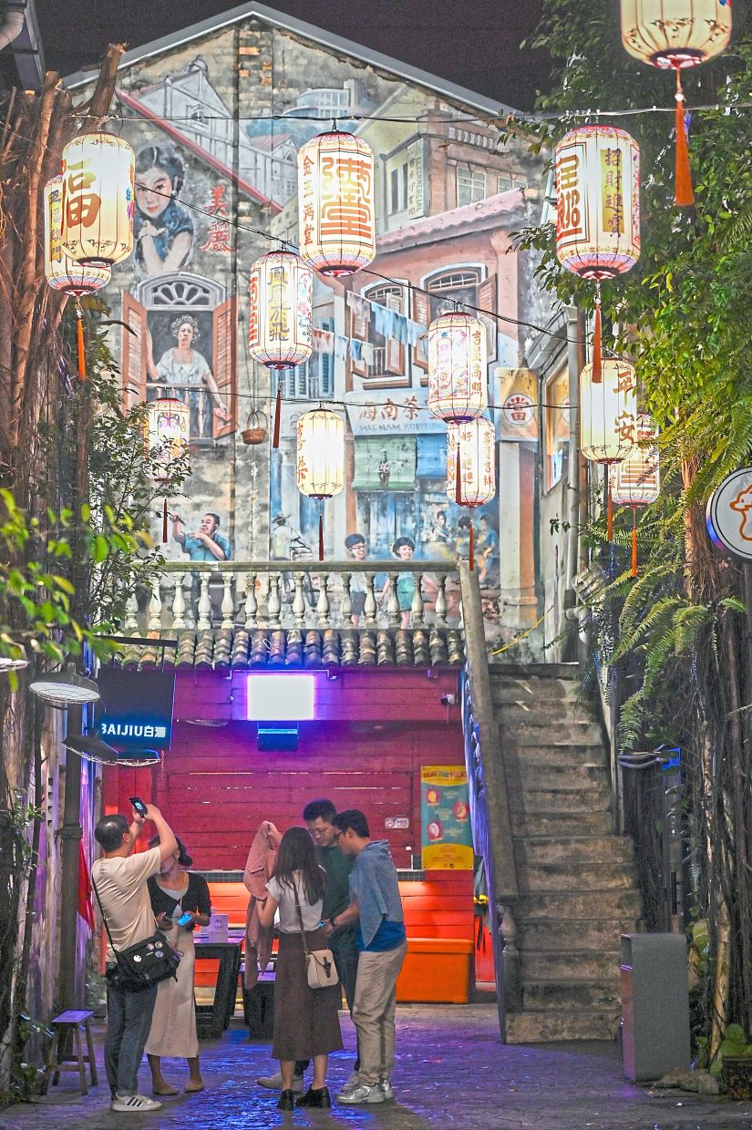 Tourists revelling in the beguiling back alley of Kwai Chai Hong with its fascinating murals and decorative lanterns.