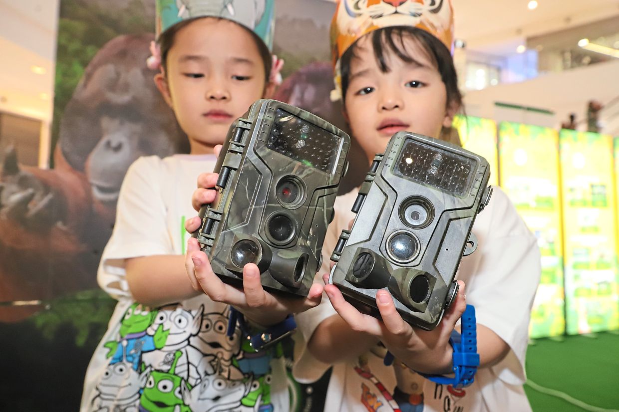 Mavis Ooi, seven, (left) and Migina Ooi, five, holding camera devices used to obtain critical data about wildlife and their habitats.