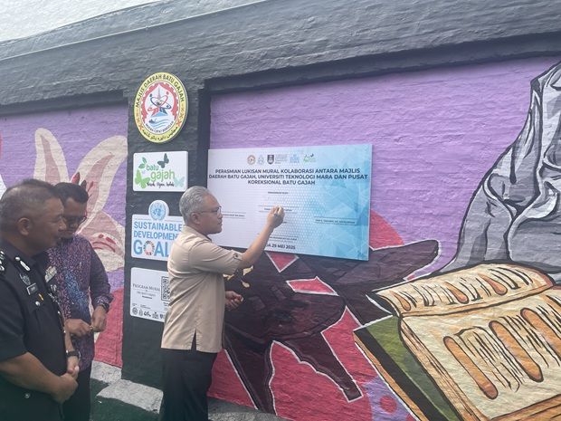 Kinta district officer Zulhisham Ahmad Shukori signing the plaque fixed outside the walls of the Batu Gajah Correctional Centre.