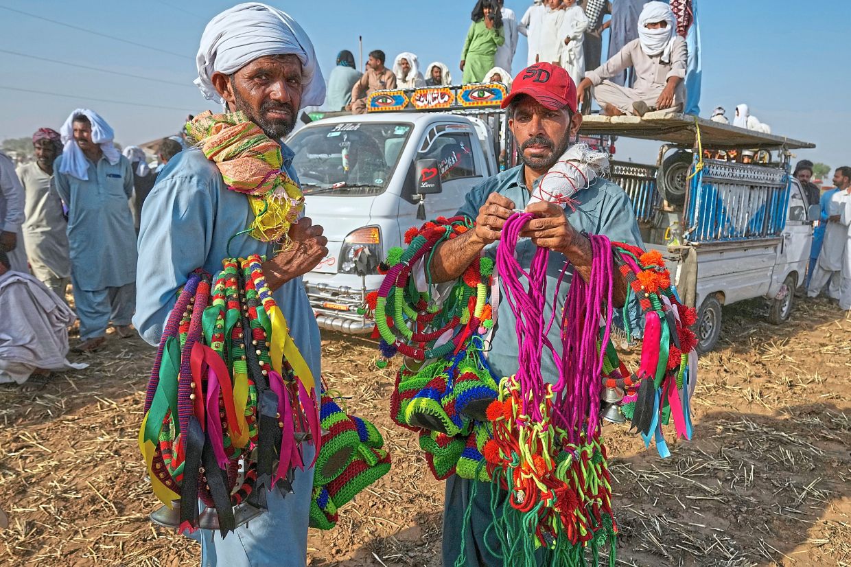 Hawkers hold colourful ribbons and other items used to decorate bulls as they wait for customers at the venue of a traditional bull race competition.