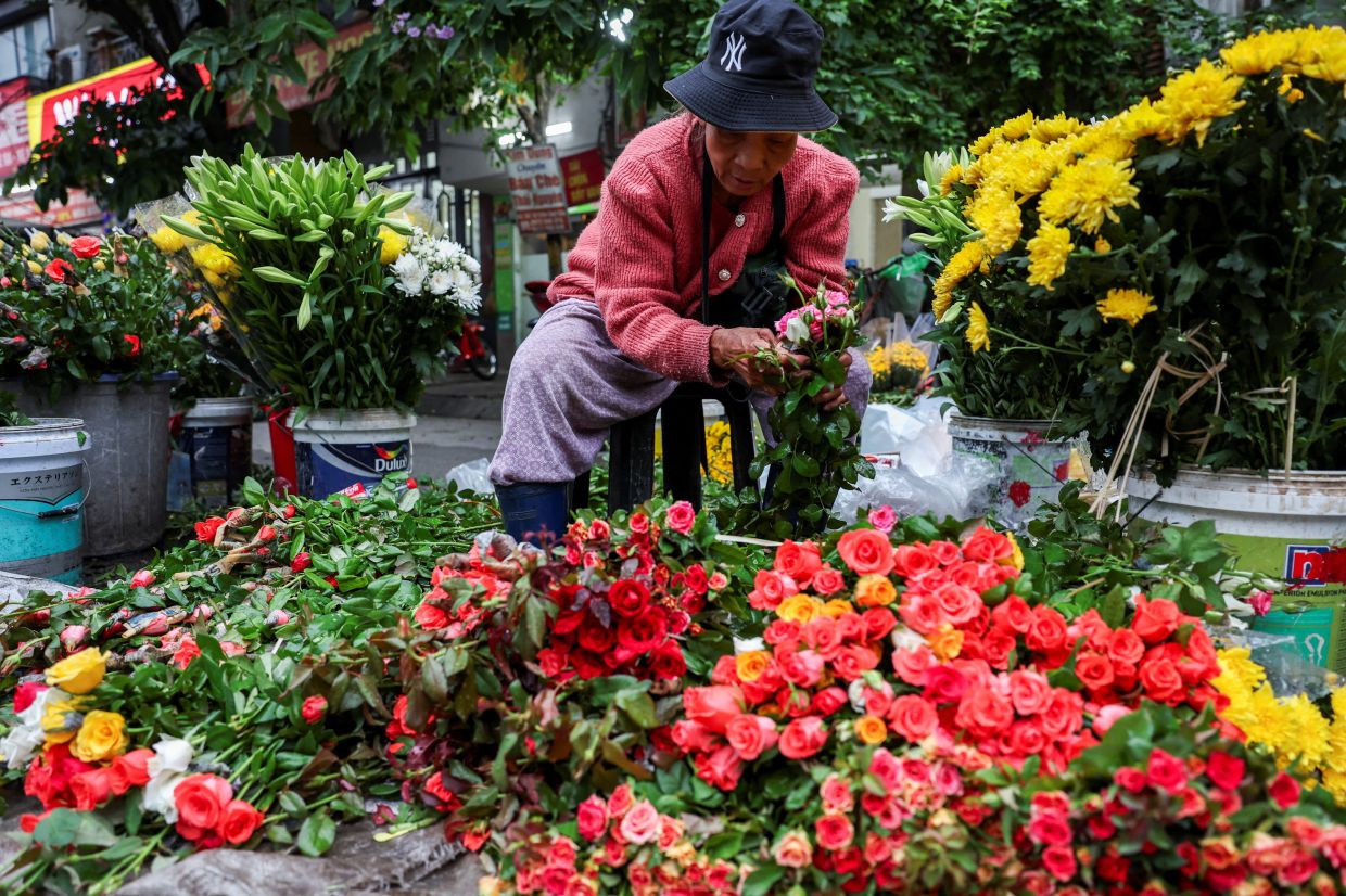 A woman prepares flowers at a local street market, in Hanoi, Vietnam. -- REUTERS/Chalinee Thirasupa