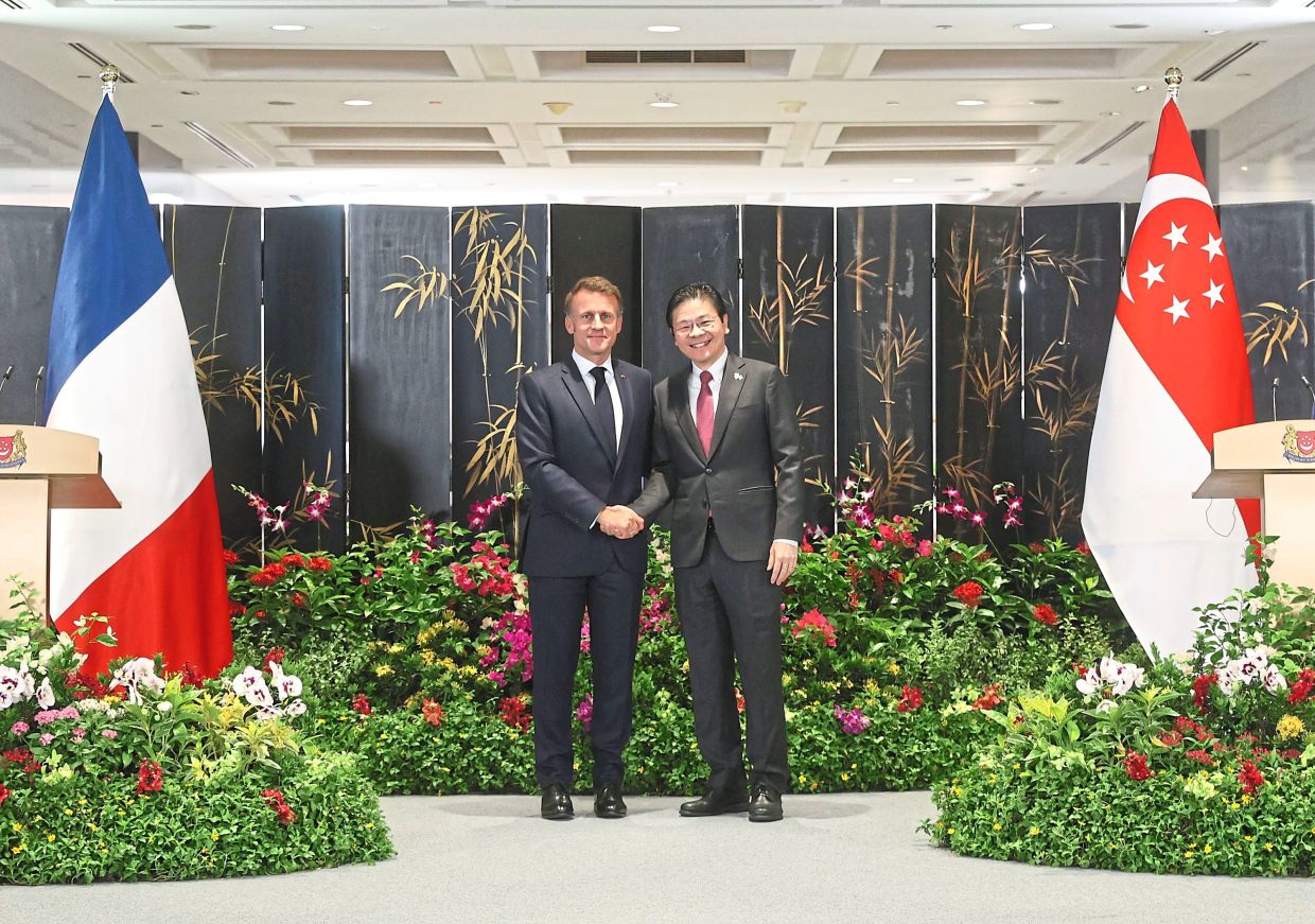 Solid partnership: Macron (left) shaking hands with Wong after both countries signed multiple bilateral agreements. — AP