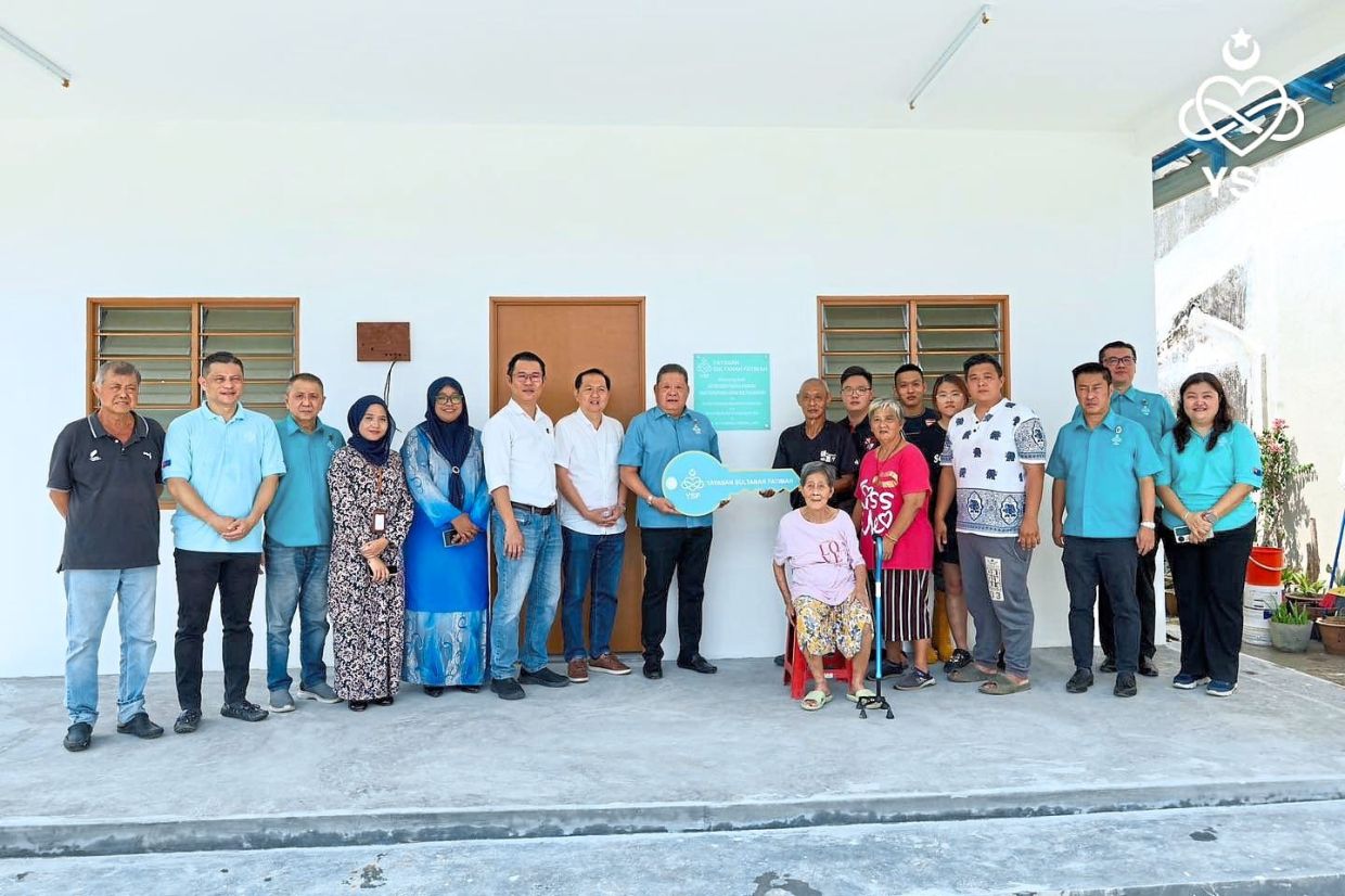 YSF chairman Wong (centre) handing over a symbolic key for a new house to a family whose home was destroyed in a fire.