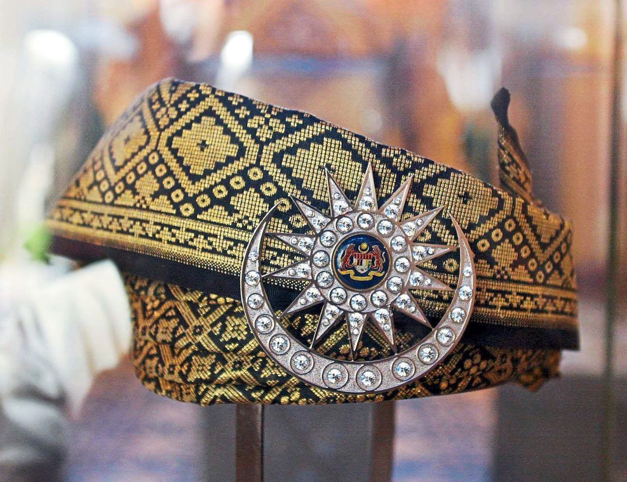 The Tengkolok Diraja is crafted from black songket embroidered with gold thread.